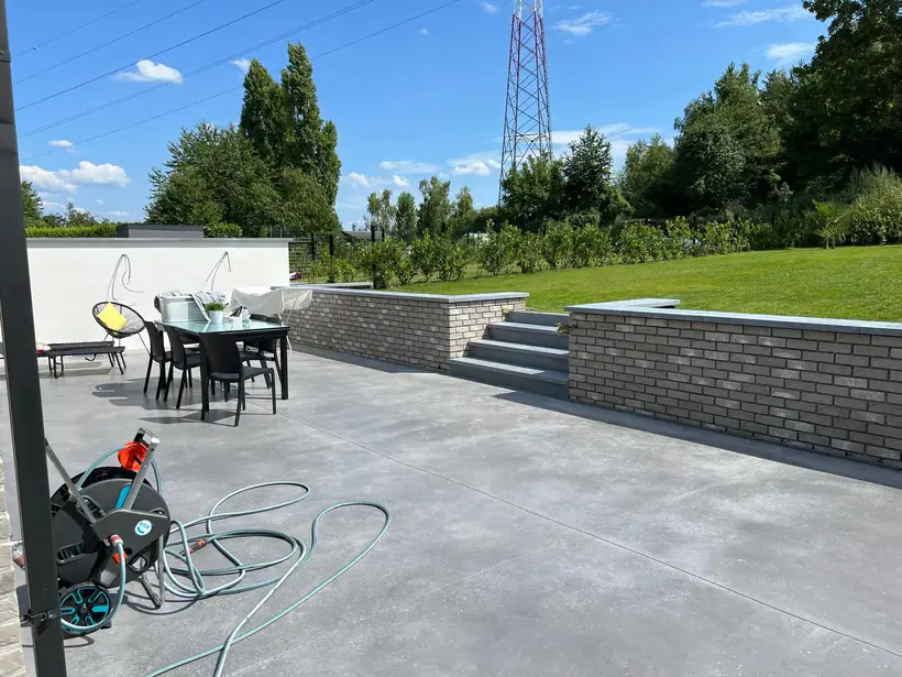 Terrasse en béton lissé bordée d'un muret en brique et d'un mur de soutènement