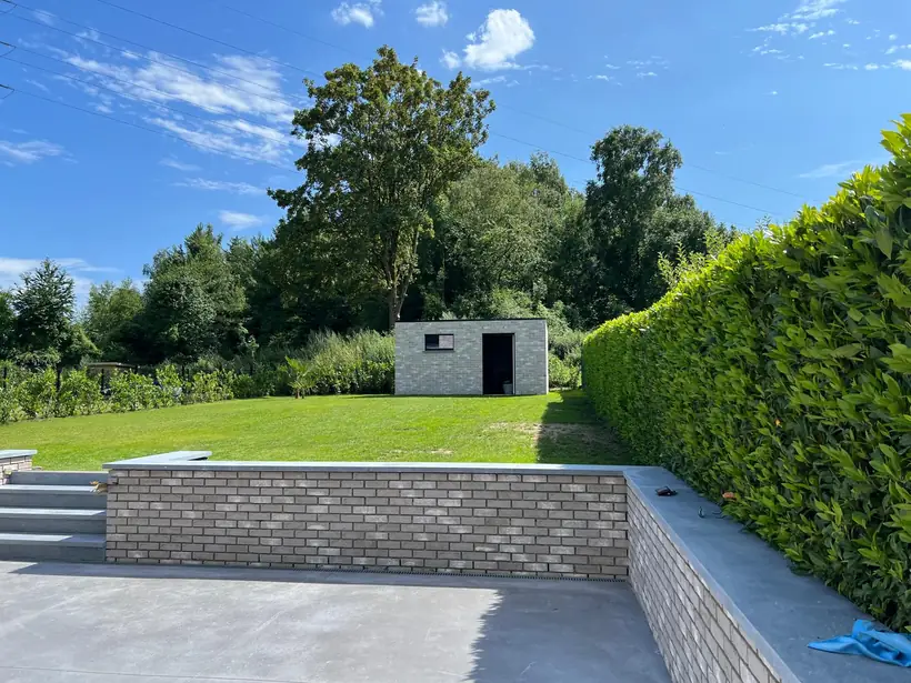 Jardin en pente retenu par un mur de soutènement en brique, avec escalier