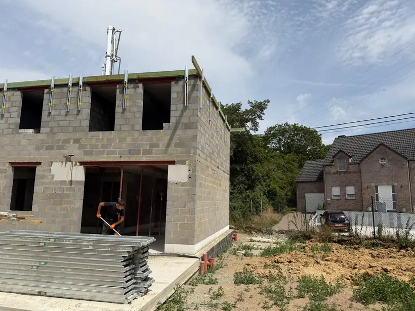 Maison à étage en blocs béton, linteaux posés et arases prêtes pour la toiture
