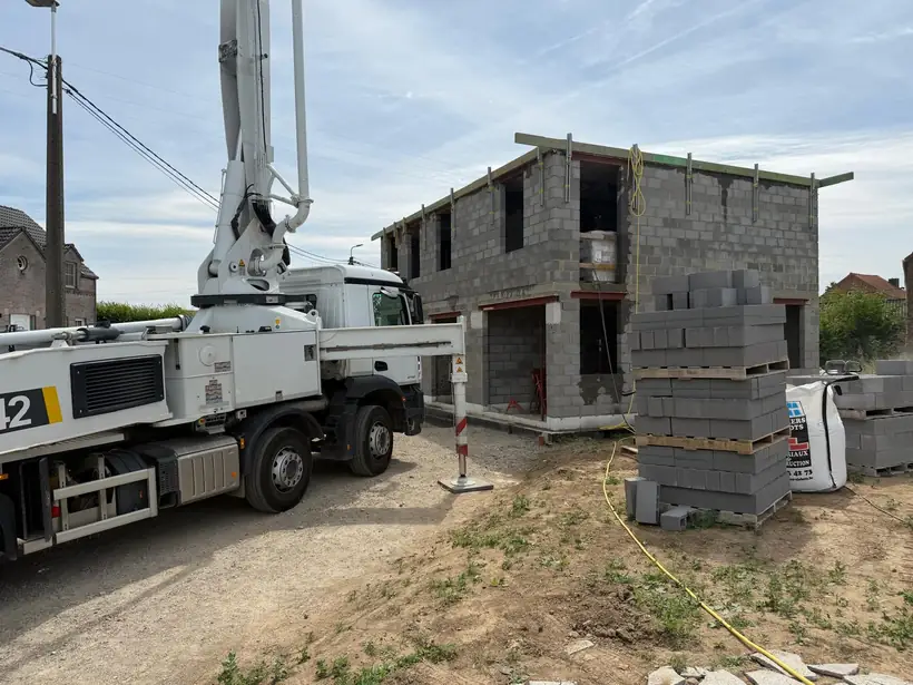 Camion pompe à béton déployé devant une maison en cours de gros œuvre