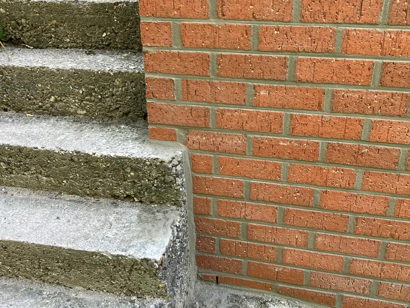 Raccord entre un escalier en béton et un mur en brique neuve, joint net